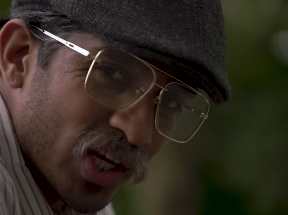 A close-up still image from the film 'Reflections' of a man's face highlighting make-up work that has significantly aged the actor's appearance